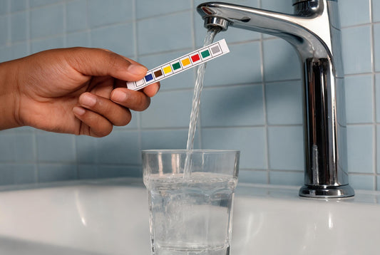 Hardness test strip held against water from an apartment bathroom tap in India
