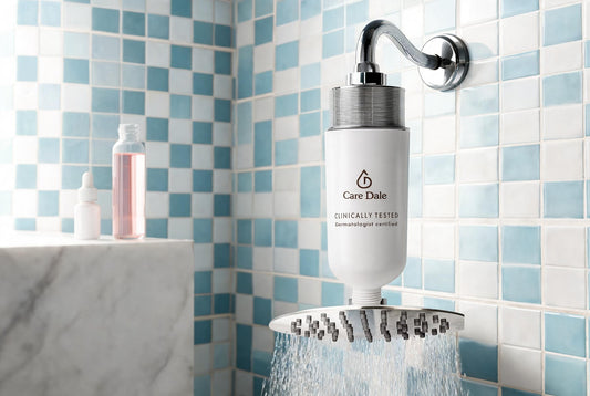 A Care Dale filter above a running rain showerhead, with a pink chlorine test sample on a marble ledge