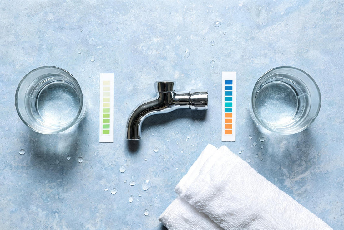 Overhead flat-lay of two glasses of Mumbai tap water, hardness colour charts and a chrome bathroom tap
