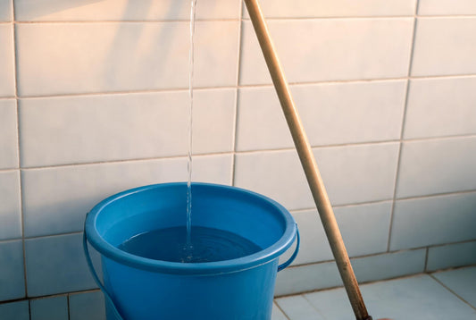 Bucket collecting RO reject water below a bathroom tap, showing why concentrated reject water suits floors not skin